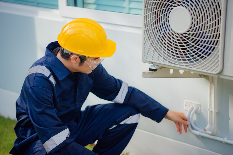 Male technician checking a cooling pipeline of the air conditioner outdoors.